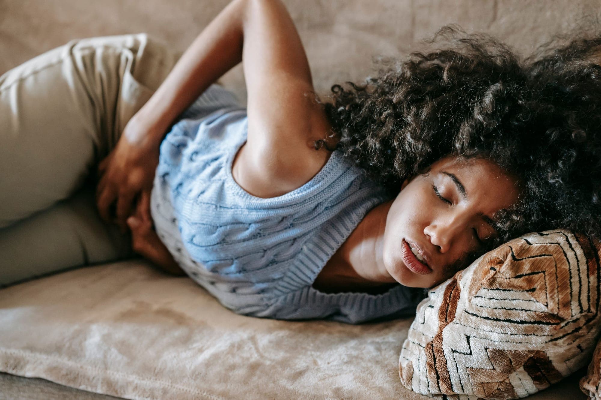Illustration pour Troubles digestifs : femme sur le canapé, les mains sur le ventre