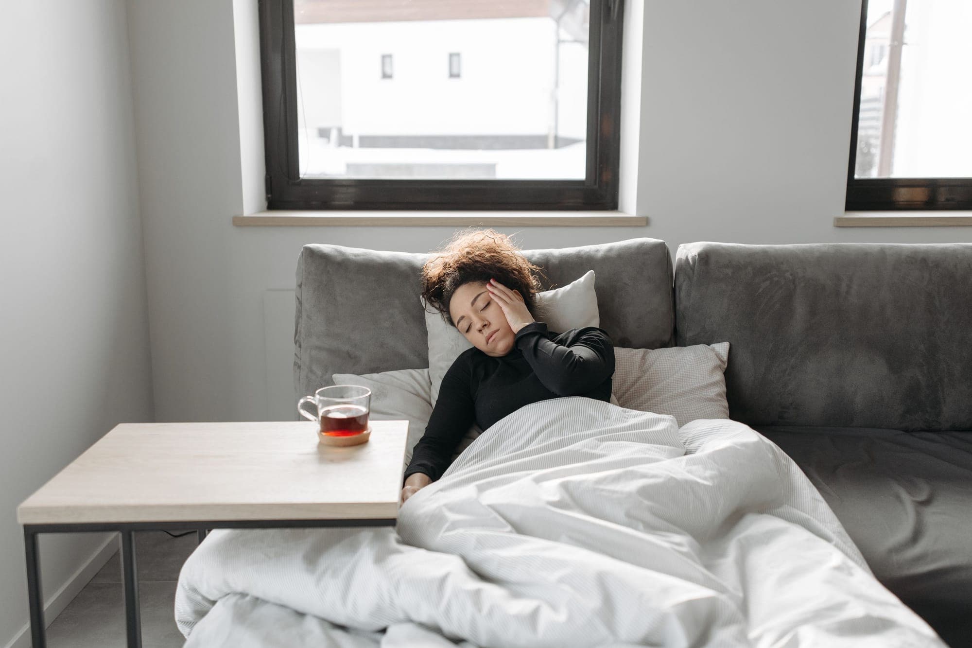 Illustration pour Infections à répétition : femme enrhumée qui se repose sur le canapé avec un thé