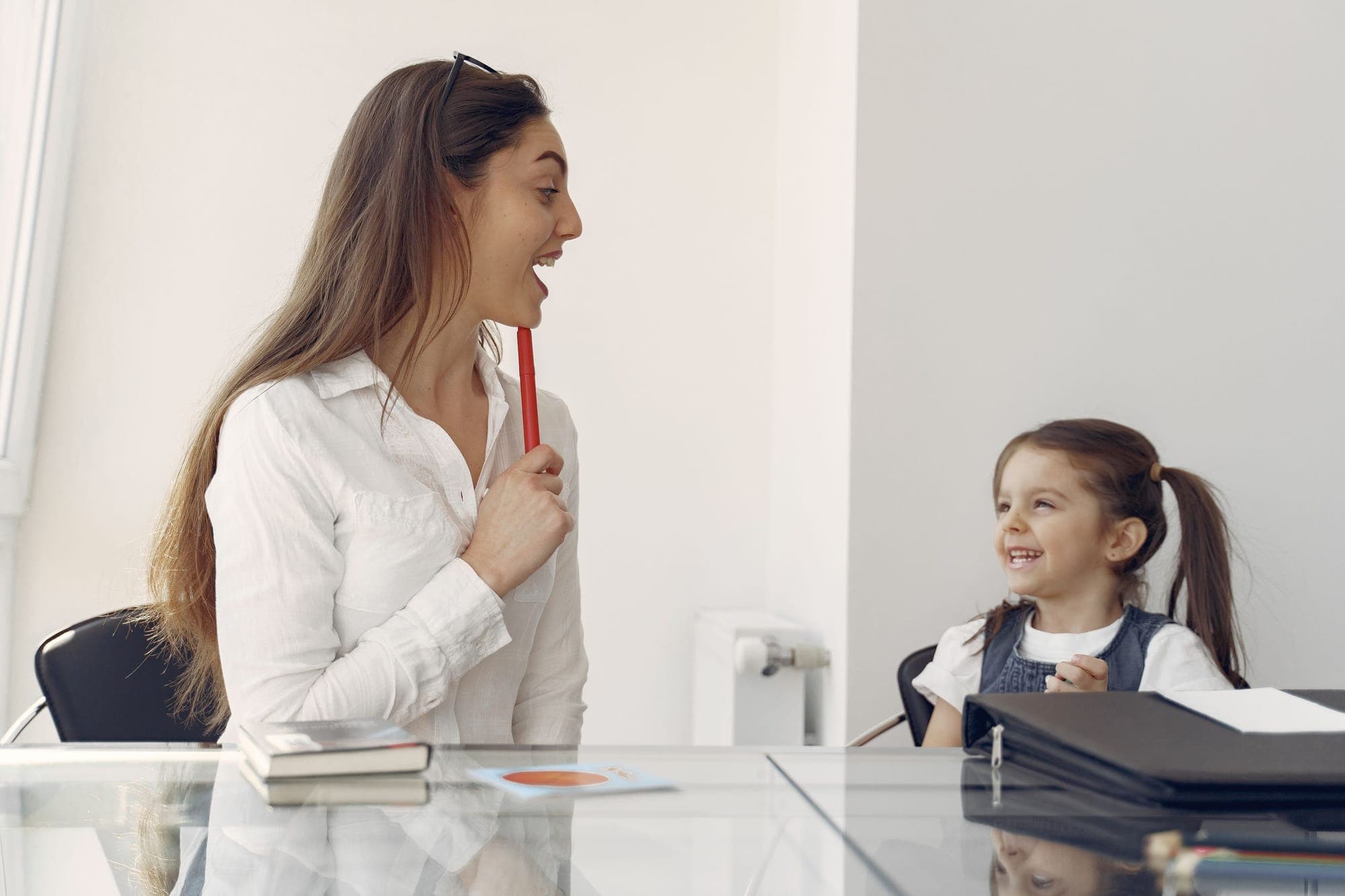 Illustration for Speech and language problems: speech therapist showing a laughing girl a mouth exercise